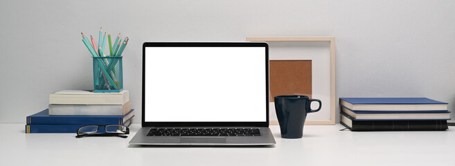 Horizontal photo of mockup laptop computer and office supplies on white office desk.