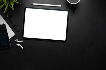 Mock up digital tablet with blank screen, stylus pen, wireless earphone and copy space on dark...