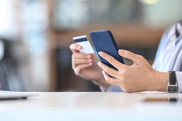 Cropped shot of young woman holding smart phone and credit card for shopping online.