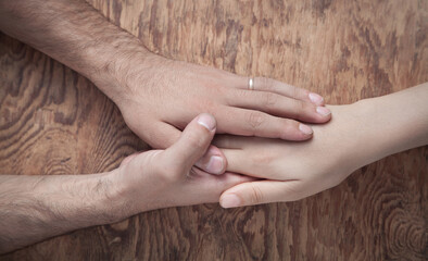 Young couple holding hands on wooden background.