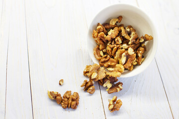 walnuts in the white bowl close. peeled walnuts on white colored old vintage wooden backdrop.