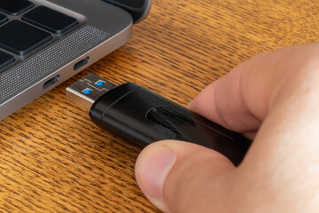 Usb a flash memory stick connecting to usb c laptop port. Lack of ports on modern laptops concept. Incompatibility of computer interfaces concept.