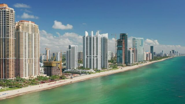Scenic Miami skyline. Beautiful modern cityscape, aerial drone water footage. Cinematic white tall design buildings at the beach with ocean view apartment. USA travel background. Florida vacation 4K.