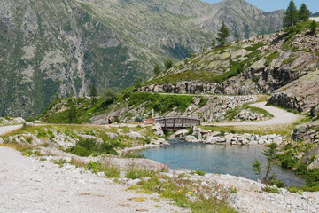 Ponte in legno che attraversa il fiume e bellissima vista sulle montagne dal sentiero che porta ai laghi Cornisello nella Val Nambrone in Trentino, viaggi e paesaggi in Italia