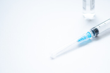 Syringe with needle and cover or top, vial or phial on a white empty space background ready to be used. Covid or Coronavirus vaccine or monoclonal antibodies background, close up