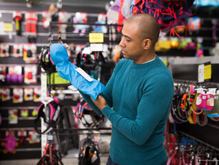 Emotional man choosing dog clothes in pet supplies store