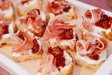 Catering. baguette with curd cheese, dried tomatoes and bacon. portioned serving of dishes. service...