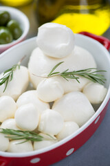 Close-up of mozzarella balls of different sizes with fresh rosemary, vertical shot, selective focus