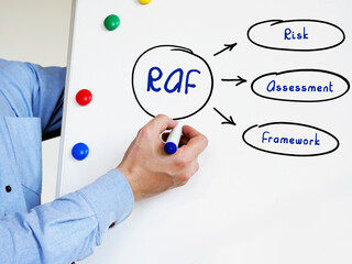  RAF Risk Assessment Framework written text. Male hand with marker write on the white board.