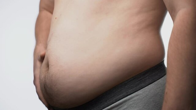 Close up of a big male stomach. The fat man checks his waist f