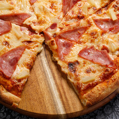 Pepperoni pizza, on a black textured background. Italian food concept. Square. Close-up.