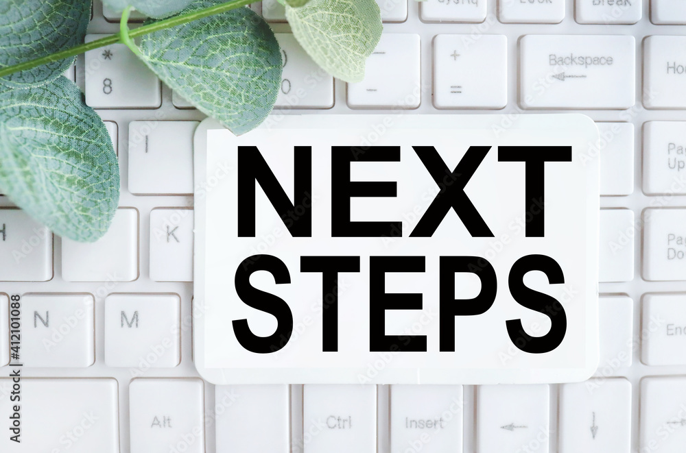 Poster next steps. text on white paper on white keyboard