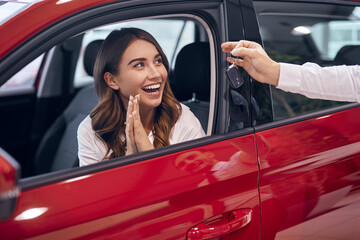 Excited woman receiving key from just bought car