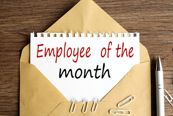employee of the month. text on white notepad paper on craft envelope on wood background.