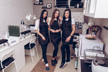Portrait of happy professional manicurists at workplace inviting to salon. Professional manicurist in special uniform at his workplace in a beauty salon