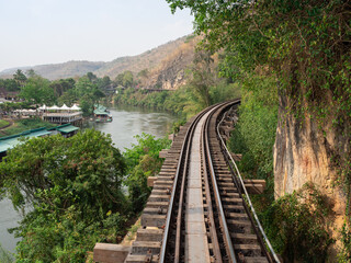 Fototapeta na wymiar Trains-eye view of railroad tracks going through a rocky pass mountain near river.