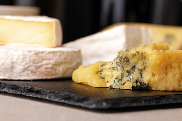 Several different pieces of cheese served on black stone flat plate