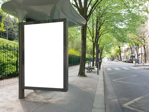 Bus stop billboard Mockup in empty street in Paris. Parisian style hoarding advertisement close to a park in beautiful city