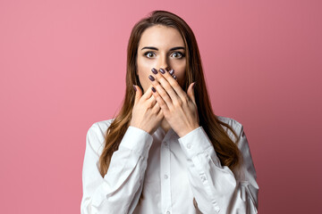 Portrait of scared brunette girl hold hands near mouth trembling fear, standing in stupor over pink background