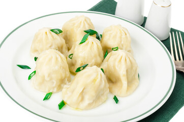 White plate with boiled khinkali, green onions.