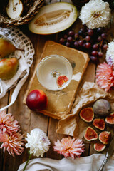 a glass of white wine with a slice of figs on a decorated fruit plate