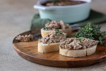 Ciabatta with chicken or turkey liver pate with thyme, concrete background.
