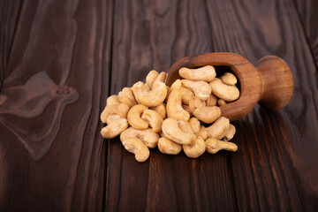 Cashew nuts in wooden scoop, on wooden background. Roasted cashew nuts.