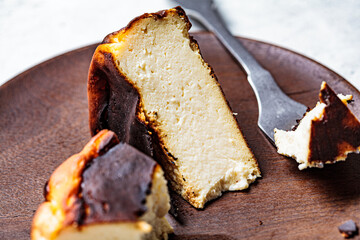 Piece of Basque burnt cheesecake on wooden plate. Spanish cuisine concept.
