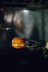 a man's hand in a black glove touches a burger