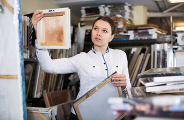 Adult woman is standing with modern pictures in furniture store