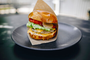 juicy burger in brown paper on a black plate
