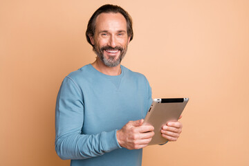 Photo portrait of businessman using tablet working on project smiling isolated on pastel beige color background