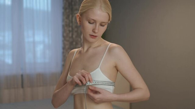 Slim sport girl front tanned body in white underwear doing measures chest