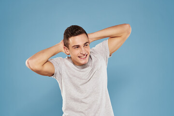 cheerful man in a white t-shirt gesturing with his hands emotions blue background