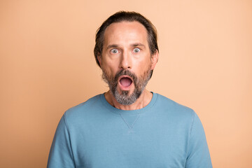 Photo portrait of shocked man with open mouth isolated on pastel beige colored background