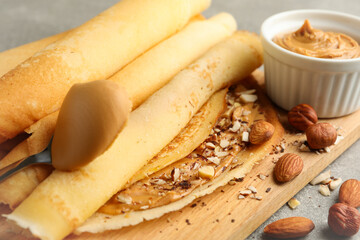 Concept of delicious breakfast with crepes with peanut butter and nuts on gray table