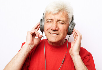 Lifestyle, tehnology and old people concept: Handsome old man in casual wear and headphones is listening to music