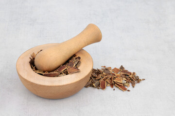 Cascara herb bark used in herbal medicine to treat constipation in a wooden mortar with pestle and...