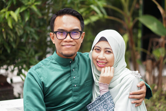 Portrait of a Muslim Malay couple wearing Malay traditional attire with happy smile face on a park celebrating their love and happiness during eid mubarak.