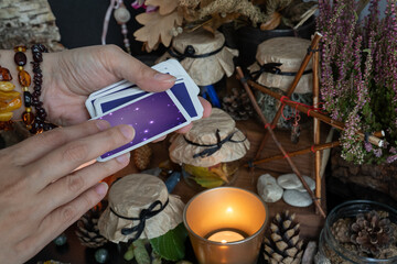 Woman hand is holding deck of tarot or oracle cards performing fortunetelling.