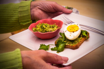 woman holding guacamole toast with boiled egg