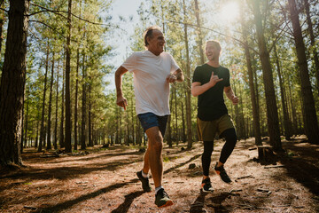 Caucasian elderly father and active son running in forest determined to exercise 