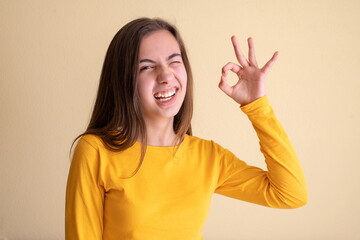 Young woman having fun and saying ok with her fingers while winking