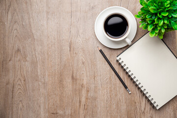 Flat lay, top view office table desk. Workspace with, laptop,office supplies, pencil, green leaf, and coffee cup on wood background.