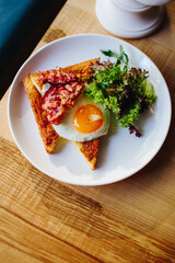 Breakfast with bacon, standing on the table, in a plate is a cherry tomato with herbs