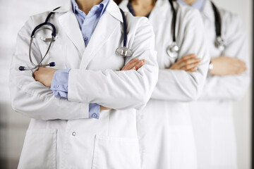 Group of modern doctors standing as a team with arms crossed in hospital office and ready to help patients. Medical help, insurance in health care, best disease treatment and medicine concept