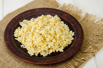 Boiled bulgur groats, vegetarian porridgeon plate. Studio Photo