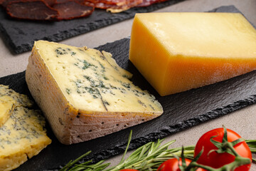 Several different pieces of cheese served on black stone flat plate
