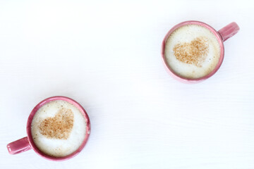 red and pink cups with coffee decorated with symbols of hearts on the table top view. for those who love a warming drink