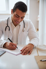Man therapist in white robe working with documents in room indoors of medicine center